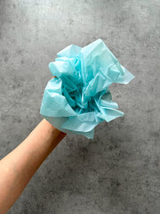 Hand holding crumpled paper on gray background, design background with space for text, plastic pollution of the planet