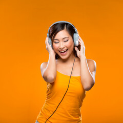 Happy Asian Woman listening to music on headphones.