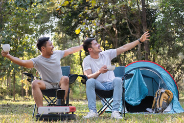 Asian LGBTQ couple drinking coffee in a romantic camping tent. LGBTQ couple drinking coffee in a camping tent, enjoying nature, forest, camping atmosphere, LGBTQ, gay, gay men.