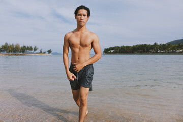 Active Asian Athlete Running on the Beach: Fit, Muscular Man Exercising in the Sand, Enjoying the Freedom of Outdoor Cardio Workouts.