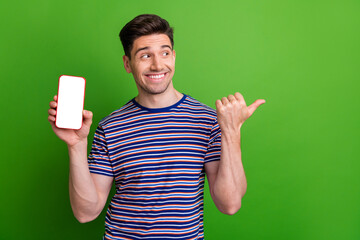 Portrait of cheerful intelligent man demonstrate smartphone screen indicating look at offer empty...