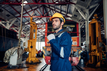 Male engineer maintenance locomotive engine wearing safety uniform, helmet and gloves work in locomotive repair garage.