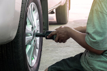 Car mechanic screwing or unscrewing car for change car tires  at repair service station