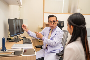 Obraz premium Mature male doctor explain to the woman patient the result of x-ray that show fracture of her calcaneus. Doctor Showing X-ray To Patient On Computer Screen.