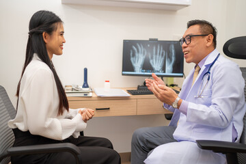 Mature male doctor explain to the woman patient the result of x-ray that show fracture of her calcaneus. Doctor Showing X-ray To Patient On Computer Screen. - obrazy, fototapety, plakaty