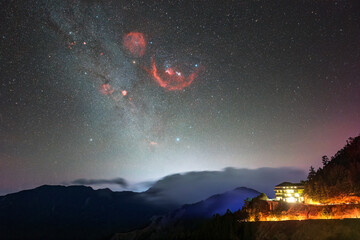 Ethereal Night Sky Over Mountain Retreat, A Cosmic Display of Stars and Nebulae
