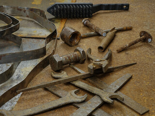Old tools and a roll of galvanized metal tape lie on a sheet of metal with traces of rust,...
