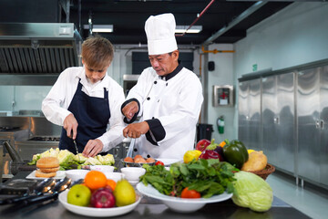 Chef teacher teaches cooking to the group children in class kitchen room.  Chef preparing student...