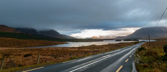 Long road with snow-capped mountains in the background and Lake Corrib in a wintry Irish scene