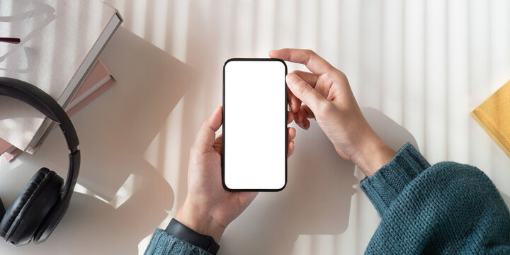Top view mockup image of a woman holding mobile phone with blank white screen while sitting