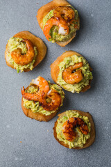 Appetizer canape with shrimp on cutting board on table close up