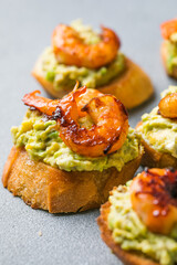 Appetizer canape with shrimp on cutting board on table close up
