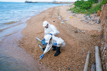Fototapeta na wymiar Scientists biologists and researchers in protective suits taking water samples from waste water from industrial. Experts analyze the water in a contaminated environment. 