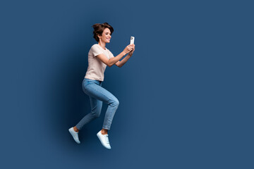 Fototapeta na wymiar Full body photo of pretty young girl running hold device shopping wear trendy white outfit isolated on dark blue color background