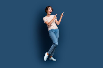 Full body photo of pretty young girl point excited empty space wear trendy white outfit isolated on dark blue color background