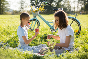 Two girls enjoy summer and vacations together spending time on green grass lawn in park,