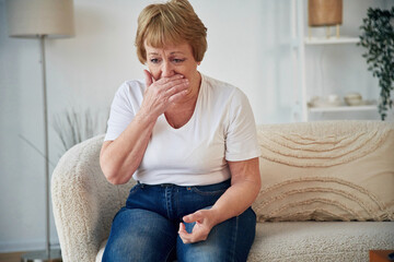 Having a cough. Feeling sick. Senior elderly woman is at home in the living room