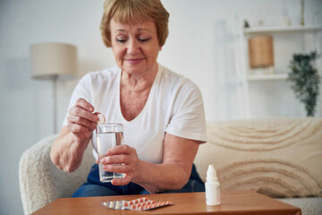 Taking the medicine, conception of illness. Senior elderly woman is at home in the living room