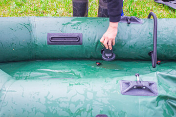 man inflating a rubber boat with a hand electric pump close-up, front and background blurred with...