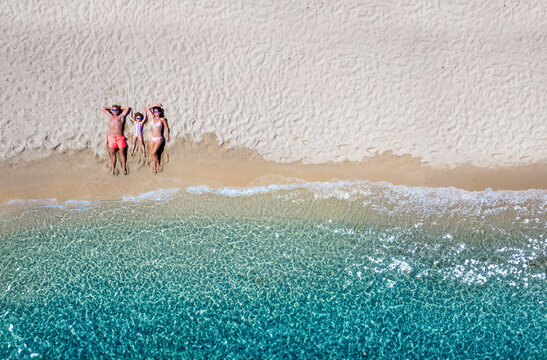 Summer holiday concept with a happy family relaxing on a beautiful beach with emerald sea, Cyclades, Greece