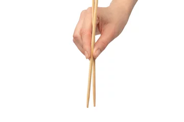Poster Female hand holding wooden sushi chopsticks isolated on white background. © Nikolay