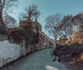 Lonely zombie on abandoned road with old buildings
