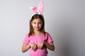 Cute girl wearing bunny ears headband posing over white background