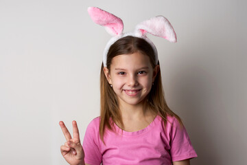 Cute girl wearing bunny ears headband posing over white background