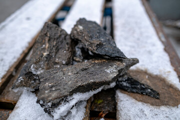 granite chips on snow covered wooden boards. Stone masonry, granite workshop. Leftovers from making stone sculpture.