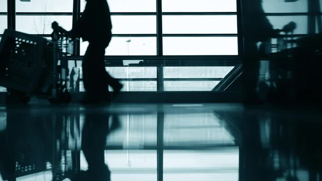 Silhouette of group of people on moving walkway at airport terminal