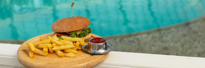 banner of tasty hamburger, appetizing french fries and ketchup. concept of relaxing and eating by the sea on a bright, hot and sunny day on the beach. soft focus