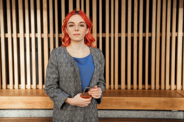Young red haired business confident  woman using smart phone outdoor of the city sunset background. 