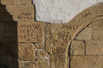 Historisches Mauerwerk aus Sandstein mit Hochwassermarken und Handwerkerzeichen und weiß verputzter Wand
