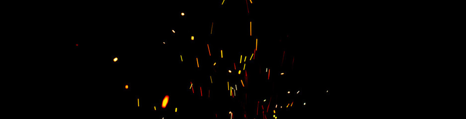 Burning red hot sparks fly from large fire in the night sky. Beautiful abstract background on the...