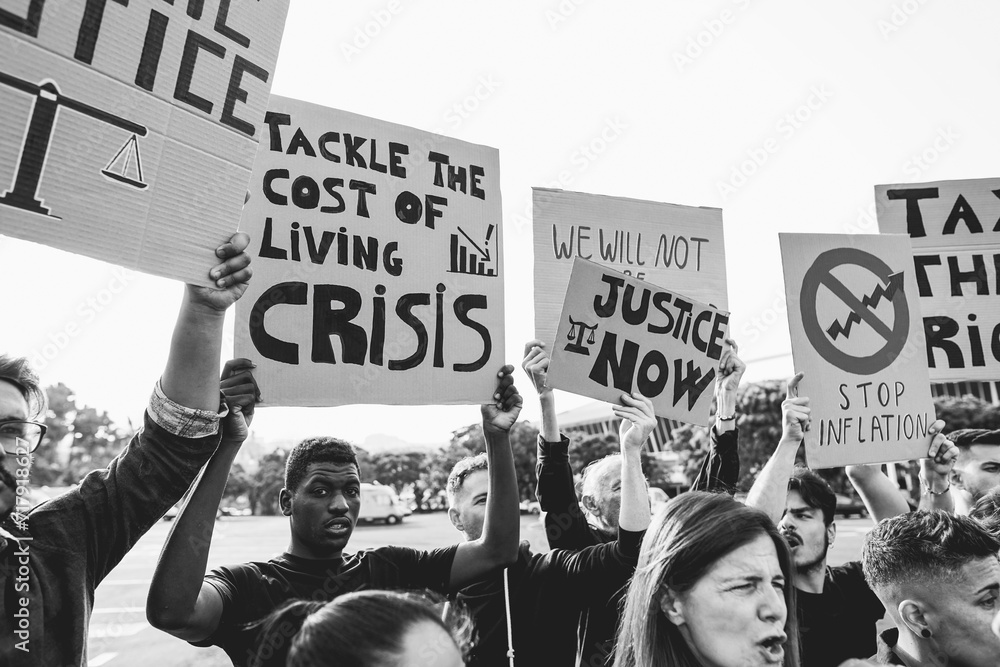 Wall mural Crowd of multiracial people protest against inflation and financial crisis - Protesters marching for rise cost of living - Focus on center banners - Black and white editng