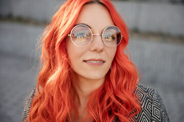 Close up portrait of young red haired business and successful woman in glasses outdoor of the city sunset background