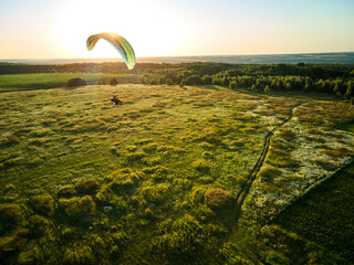 Paraglider Soaring High Above Lush Green Fields on a Sunny Day