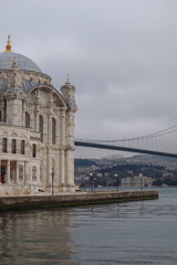 Ortakoy Mosque in Istanbul against the backdrop of the bridge in cloudy weather