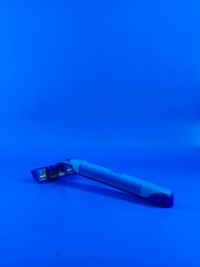 blue mustache shaving and beard trimming with used razor blade on blue background