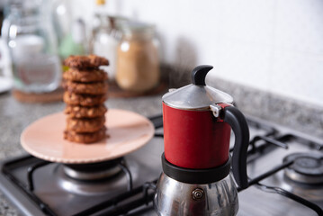 Freshly prepared cookies in the kitchen, served on a plate next to a coffee maker.