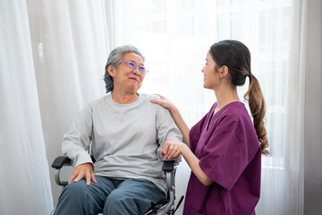 Obraz premium Asian young nurse taking care and talking mature female patient sitting on wheelchair in hospital. Healthcare concept.