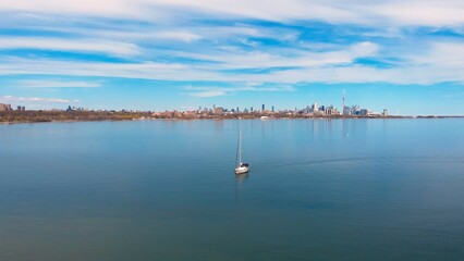 boat sailing Canadian Lake Ontario against Toronto backdrop, symbolizing journey. journey Lake Ontario, Toronto's skyline cityscape, offers scenic route, enhancing journey's allure, serene water Drone
