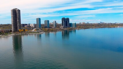 Fototapeta premium Business district's towers line calm lake shores. serene lake reflects city's bustling business skyline. perfect business harmony between urban landscape, tranquil nature commercial vigor. Drone view.