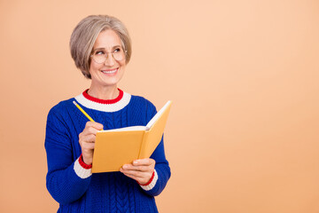 Photo of cheerful lovely senior lady hr recruiter wear blue trendy clothes hold book look empty space isolated on beige color background