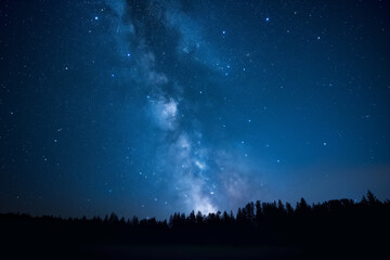 Fototapeta na wymiar Blue dark night sky with many stars above field of trees. Milkyway cosmos background