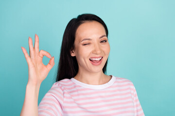 Photo of funky cool mixed race mestizo lady dressed striped t-shirt showing okey gesture winking isolated teal color background