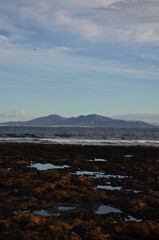 Beautiful sunrise over the Atlantic Ocean near the town of Corralejo, on Fuerteventura beach overlooking the islands of Lobos and Lanzarot. Rocky beach in the morning with a view of the rolling sea
