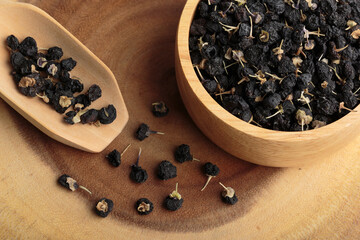 Black goji berry or black wolfberry in a wooden bowl and wooden spoon.