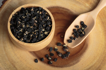 Black goji berry or black wolfberry in a wooden bowl and wooden spoon.
