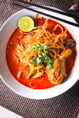 Noodles with coconut milk, or what we call khao soi, is a dish in northern Thailand. Served with red onions, crispy fried noodles and pickled vegetables, Top View